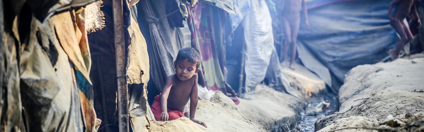 Jongen zit op de grond in vluchtelingenkamp Myanmar
