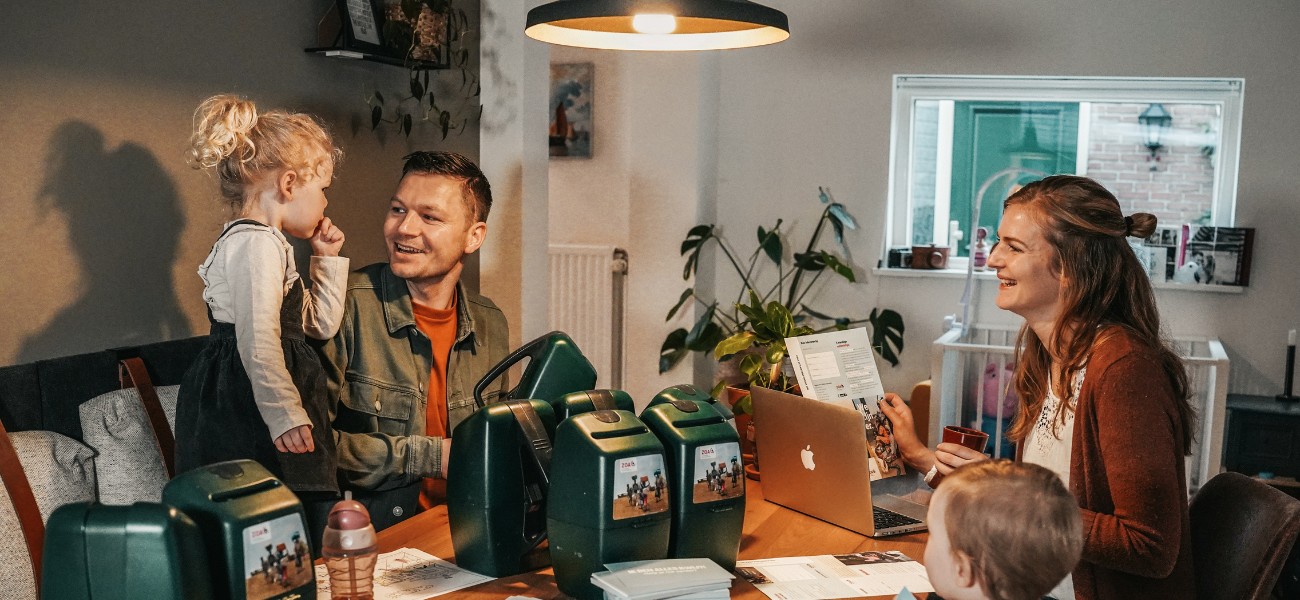 Lachend gezin aan eettafel met collectebussen
